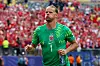 Orjan Nyland i grønn Norge-drakt feirer foran en rødkledd tribune på stadion.